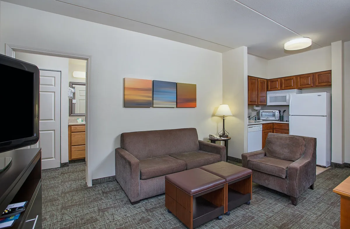 A warm and inviting living space featuring a plush sofa and coffee table, a well-equipped kitchenette for home-cooked meals, and tasteful artwork that adds a personal touch—all designed for comfort and connection.